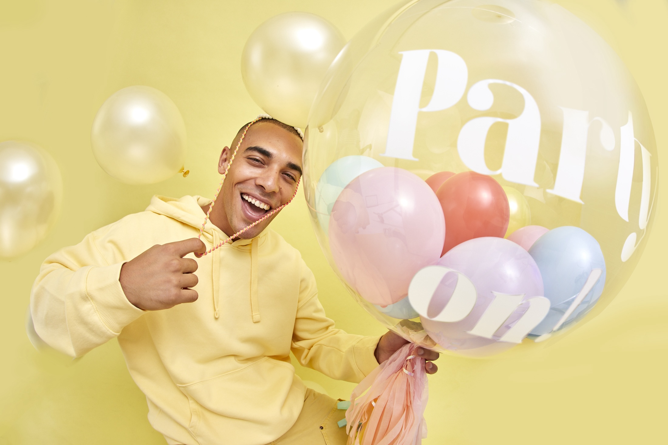 A man in yellow celebrating his birthday with a balloon